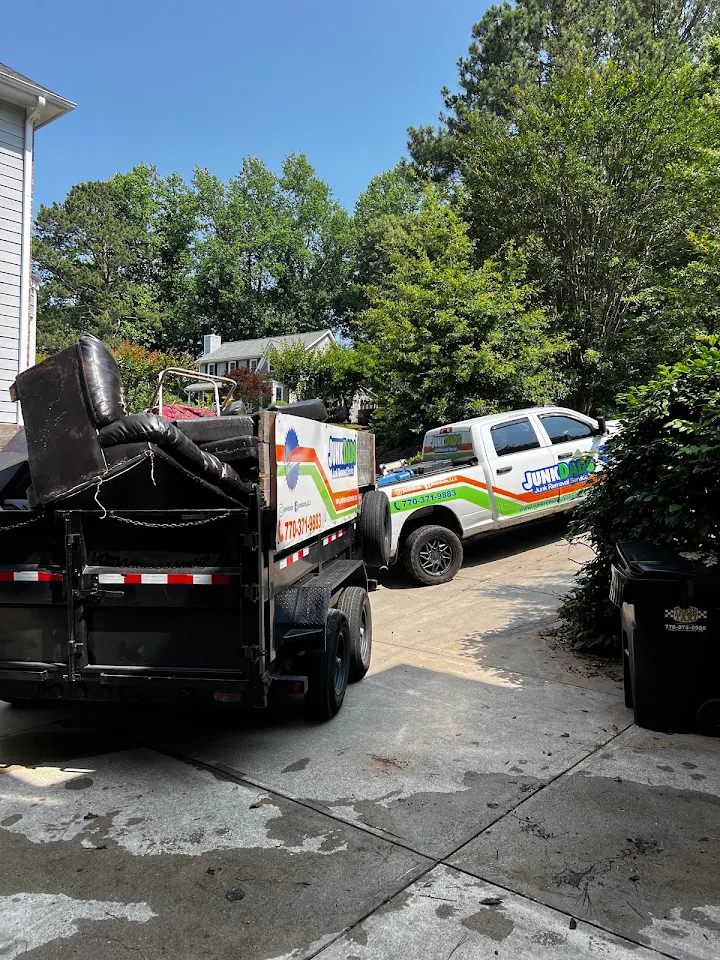 Junk Dads truck and dump trailer loaded with furniture in a driveway